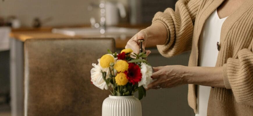 Woman Arranging a Bouquet of Flowers in a White Vase